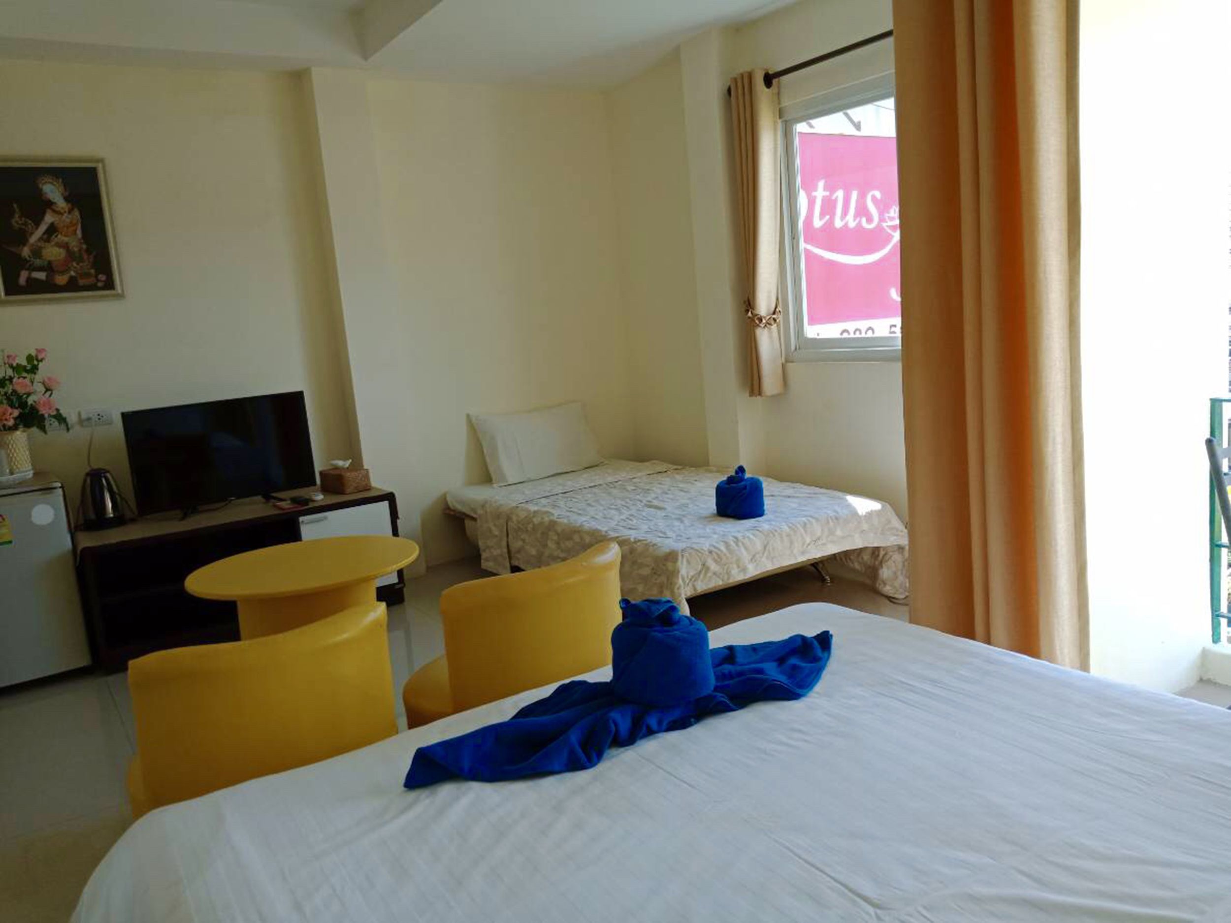 Une chambre d’hôtel avec un lit, un bureau avec une télévision, une petite table et une fenêtre avec des rideaux.
