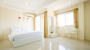 Une chambre d’hôtel moderne avec un grand lit, une petite table avec des chaises, un miroir et une fenêtre avec des rideaux.