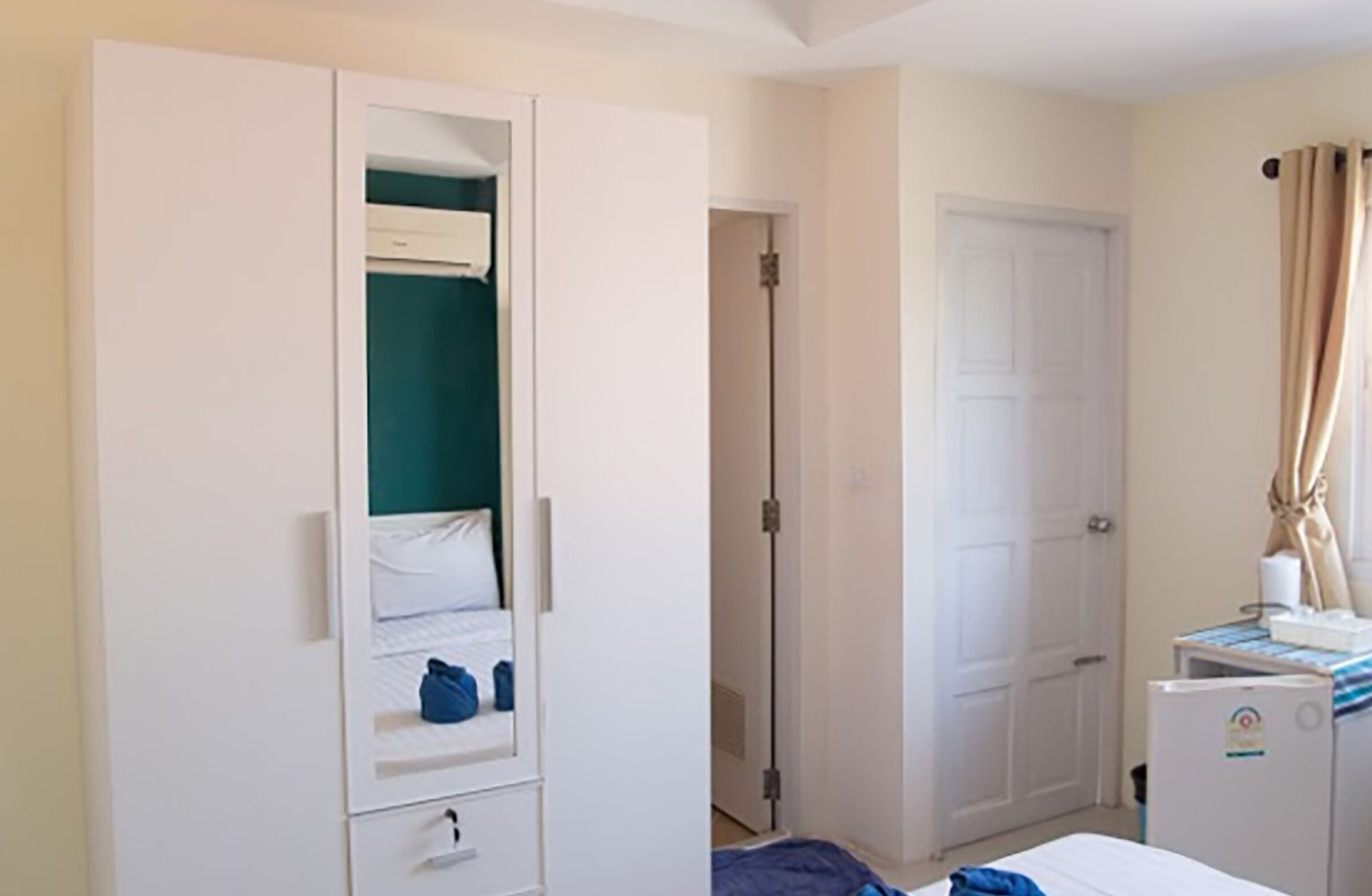 Een slaapkamer met een bed, een kledingkast, een deur en een klein tafeltje met een kopje.