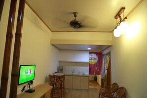 A compact kitchen with a dining area, a ceiling fan, a TV, and a small island with a sink. - Thanks Hotel (Nibong Tebal)