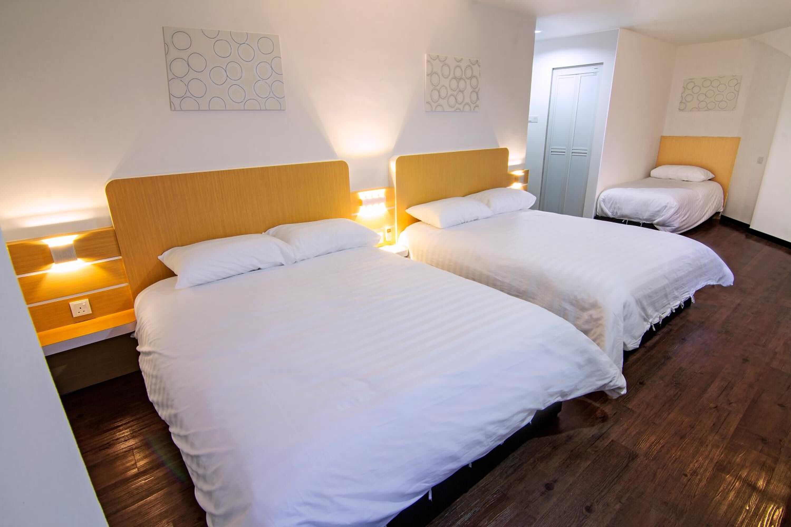 Ein Hotelzimmer mit zwei Betten, Holz-Kopfteilen, weißer Bettwäsche und Wandbildern.