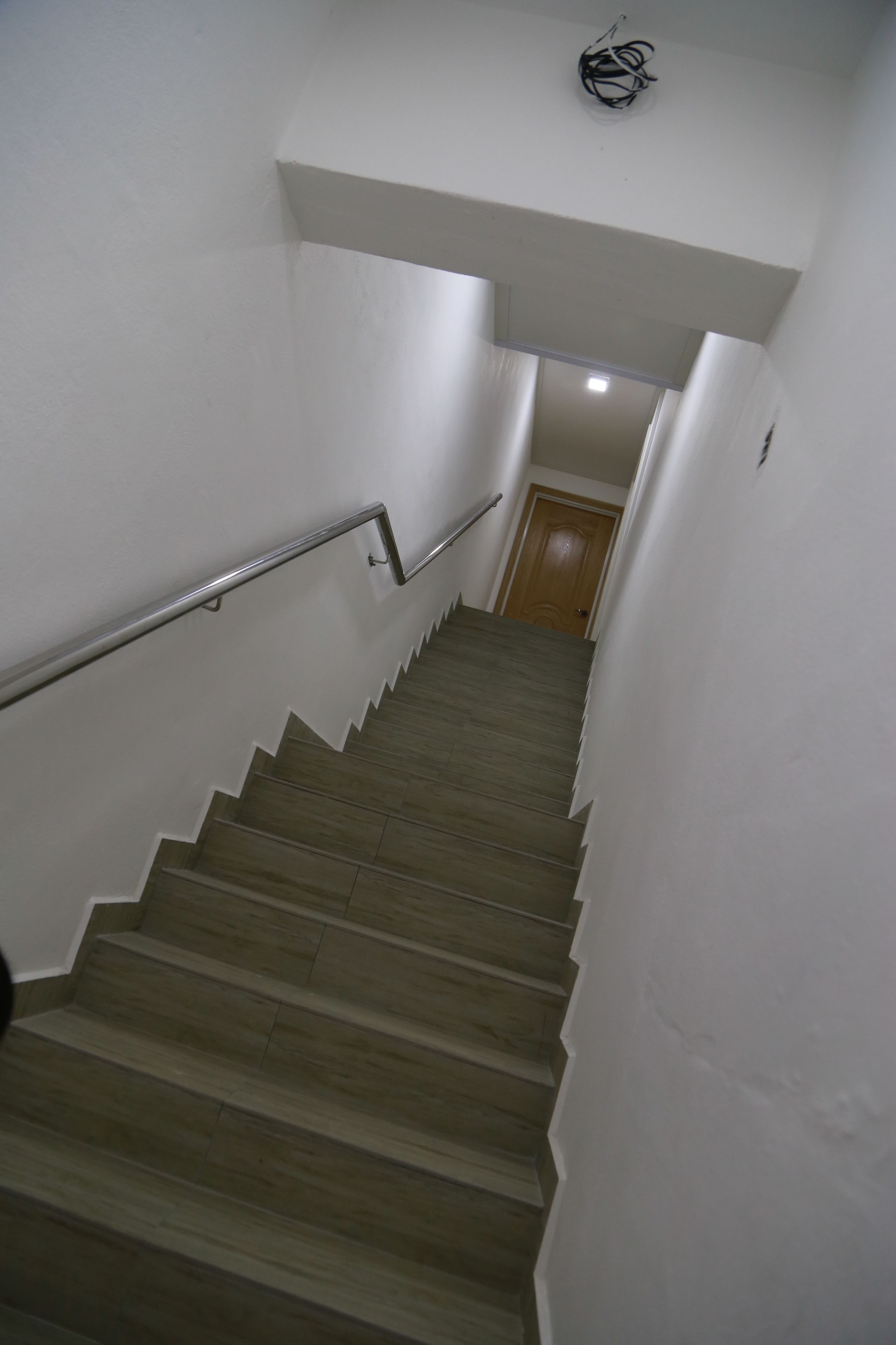 A staircase with wooden steps and metal handrails, leading to a door at the top.