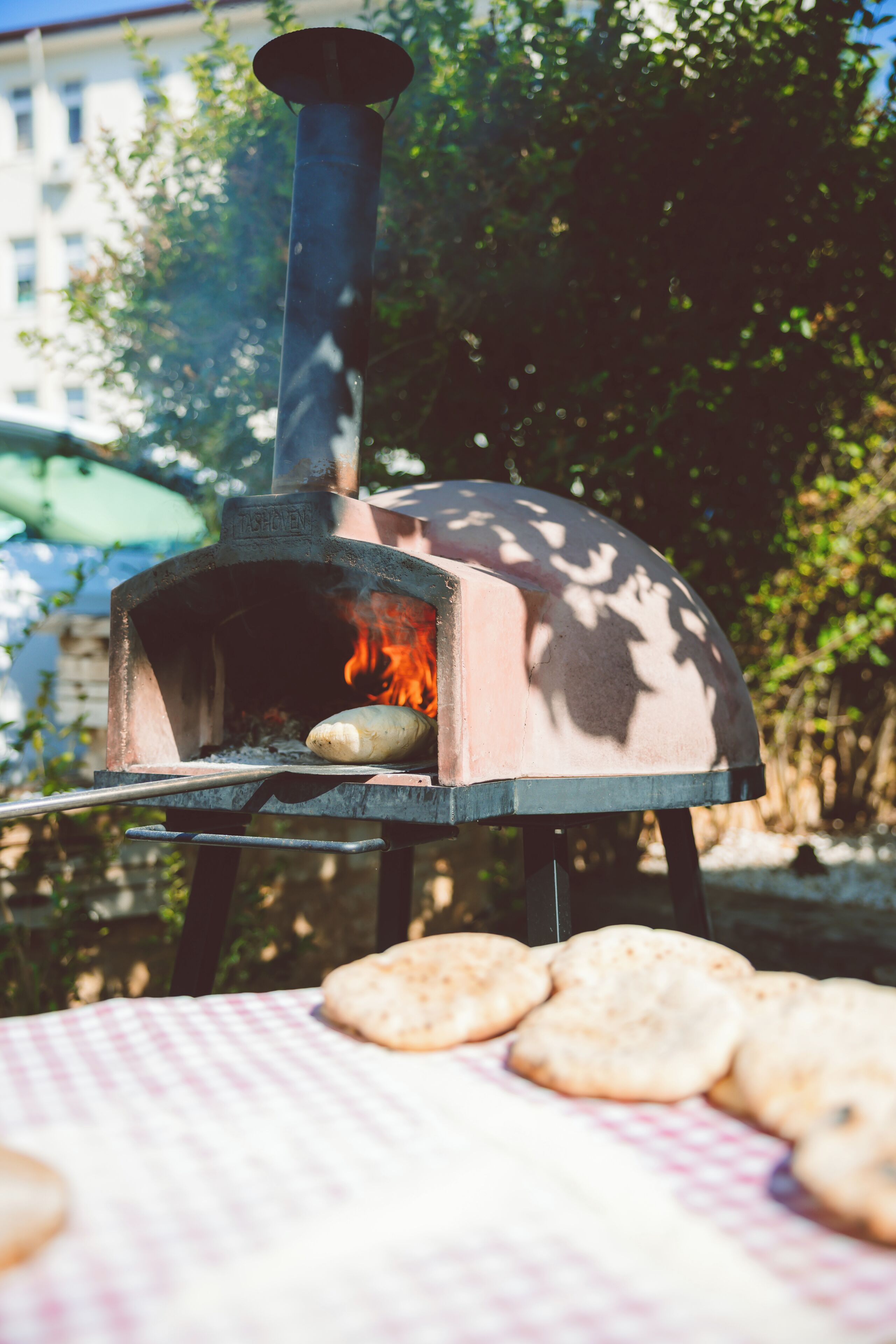 A pizza oven with a fire burning inside, surrounded by a table with several pizzas on it.