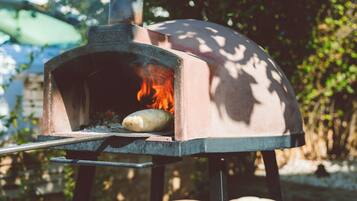 A pizza oven with a fire burning inside, surrounded by a table with several pizzas on it.