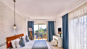 A modern hotel room with a large bed, a desk, and a balcony with blue curtains. - Arnna Hotel (Kas)