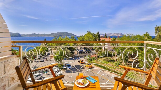 A balcony with a view of a coastal road, a dining table with a plate of food, and a chair. - Arnna Hotel (Kas)