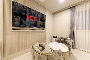 Relax in this stylish living room with a large flat-screen TV and comfortable tufted armchairs.