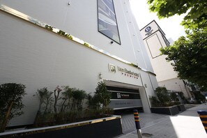 The exterior of Dan Besta Hotel with a modern facade, entrance, and surrounding greenery.