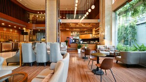 A spacious lobby with modern furniture, a bar area, and large windows offering views of greenery. - Muong Thanh Grand Sai Gon Centre Hotel (Ho Chi Minh City)