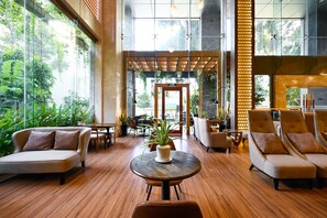Un vestíbulo amplio con piso de madera, asientos cómodos y ventanas grandes que dan a zonas verdes.