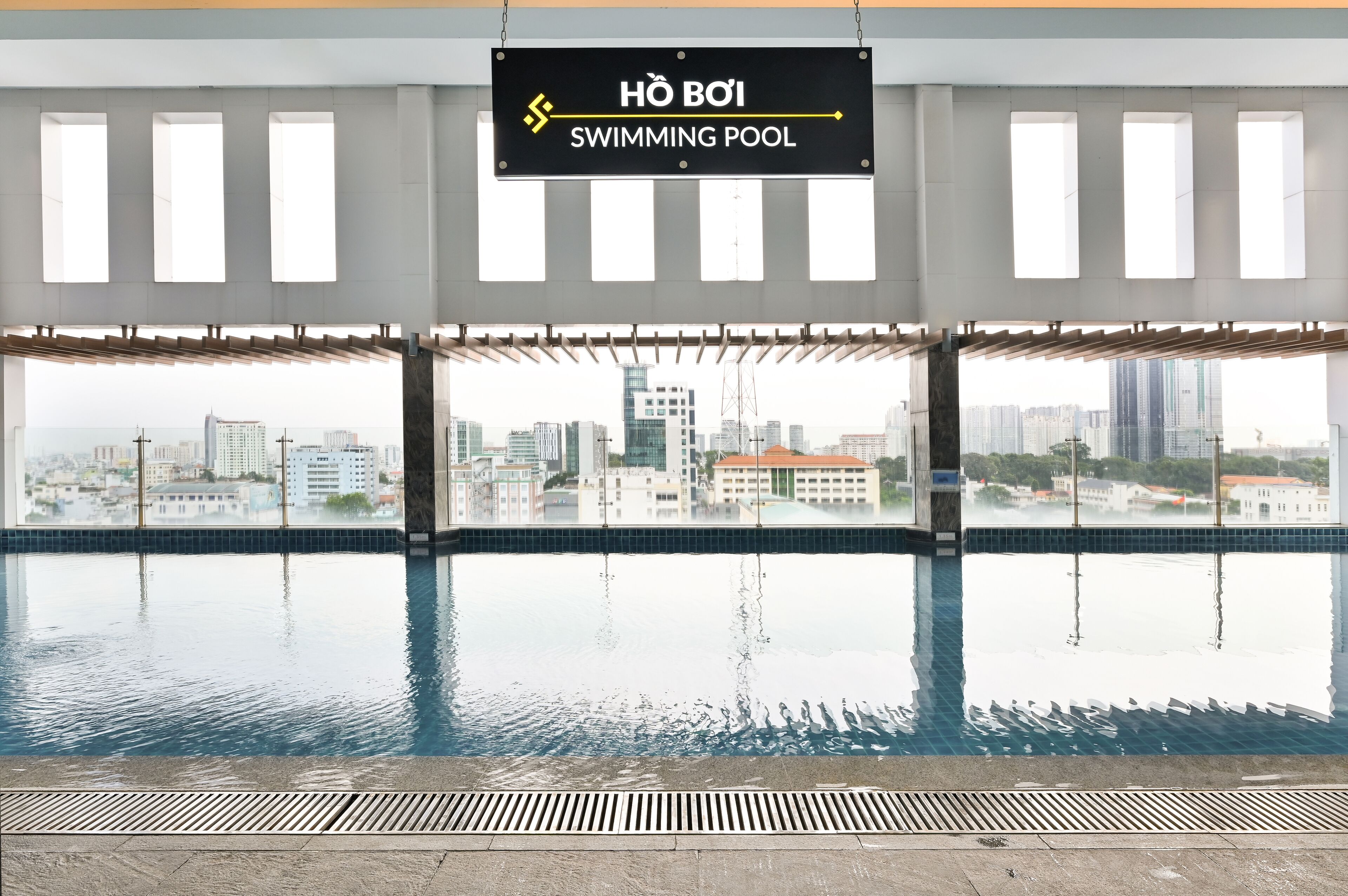 A swimming pool with a city view, a sign indicating the pool's name, and a modern architectural design.