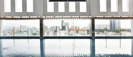A swimming pool with a city view, a sign indicating the pool's name, and a modern architectural design.