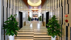 A modern hotel lobby with a black and white striped floor, a large circular ceiling light, and potted plants on either side. - Muong Thanh Grand Sai Gon Centre Hotel (Ho Chi Minh City)