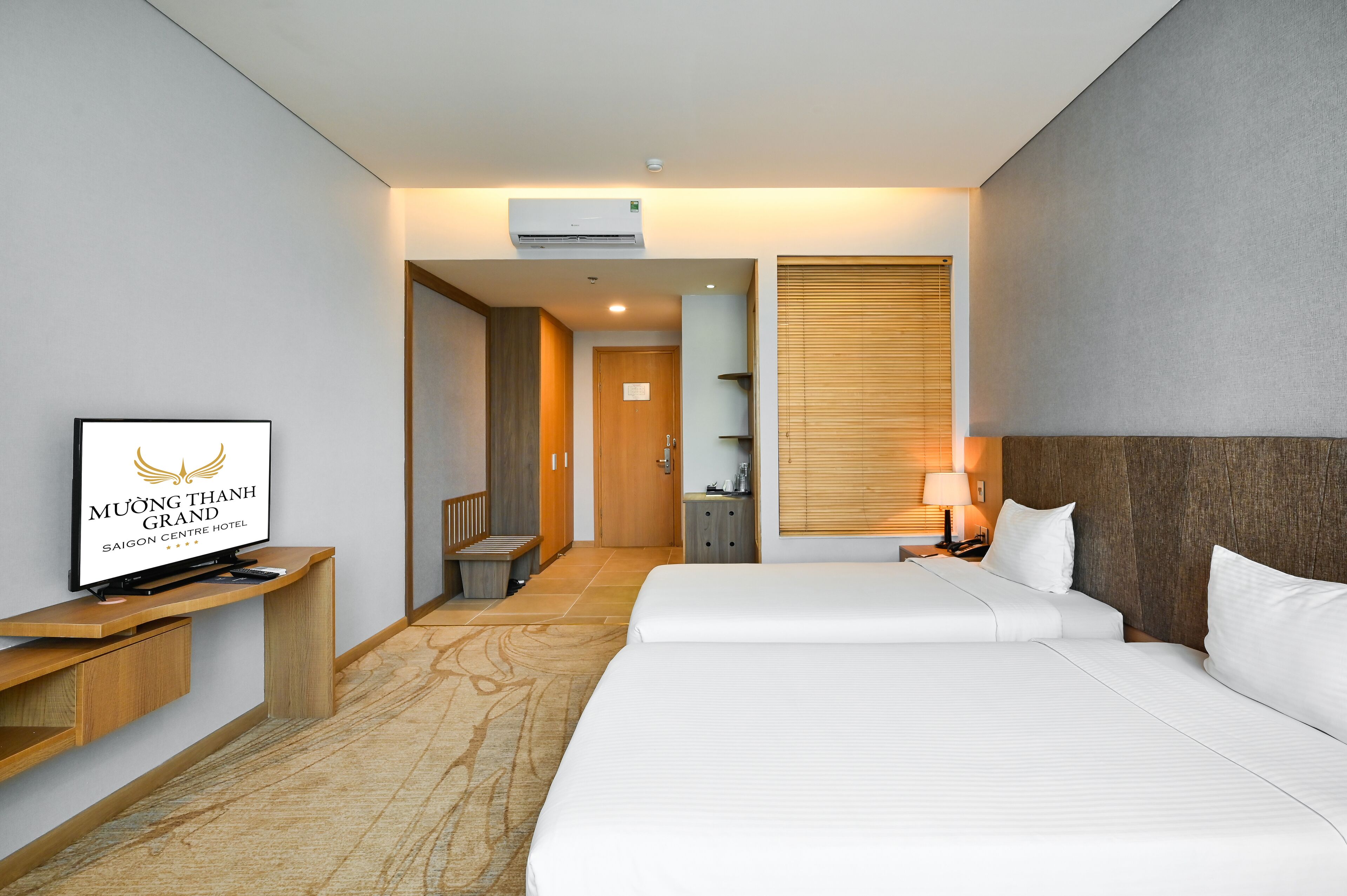 A hotel room with a bed, a TV on a wooden stand, a desk, and a bathroom visible through an open door.