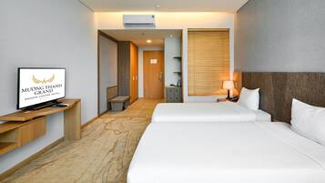 A hotel room with a bed, a TV on a wooden stand, a desk, and a bathroom visible through an open door.