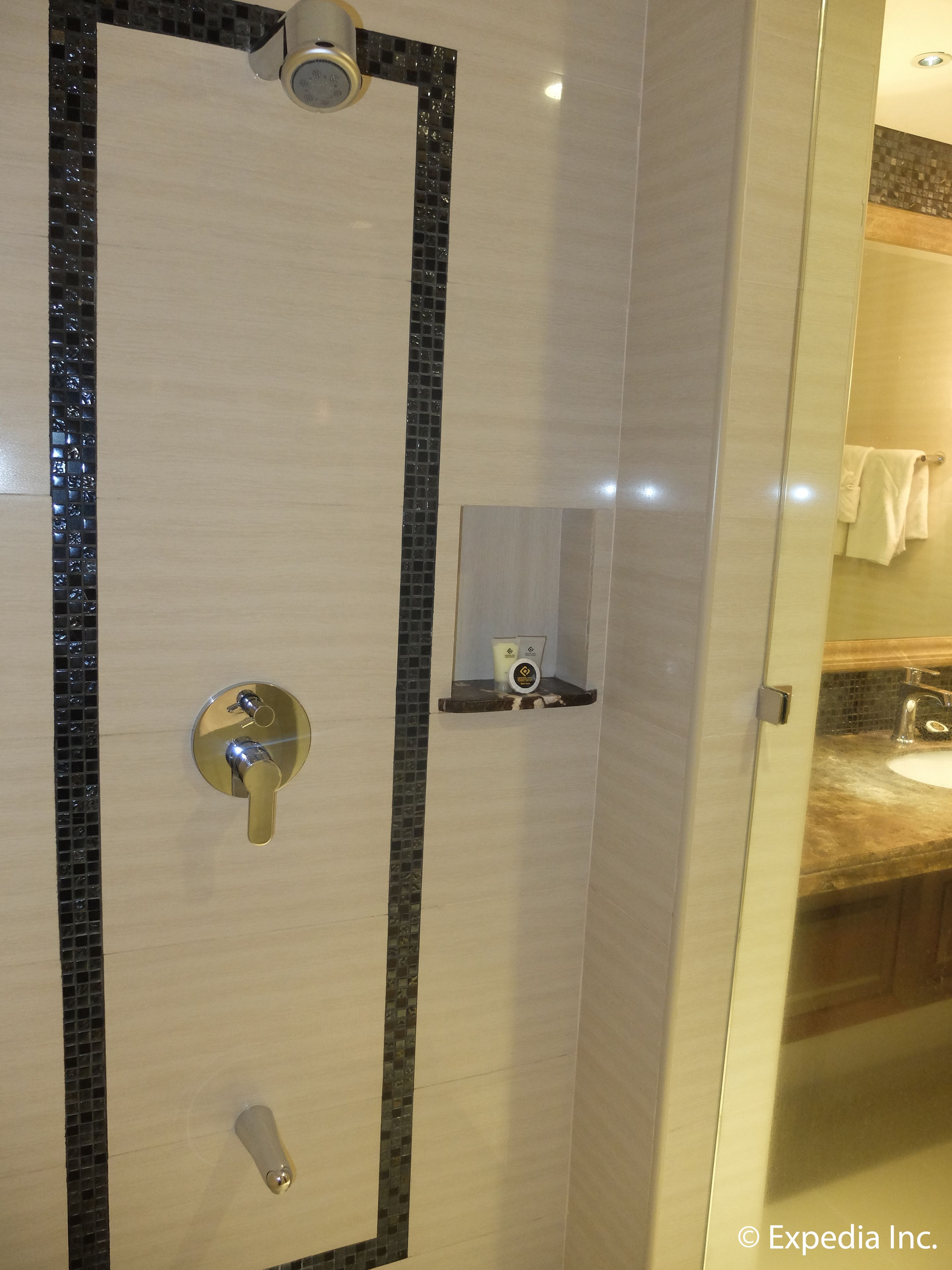 Une salle de bain moderne avec une douche à l’italienne en verre, un meuble-lavabo et une petite étagère contenant des articles de toilette.