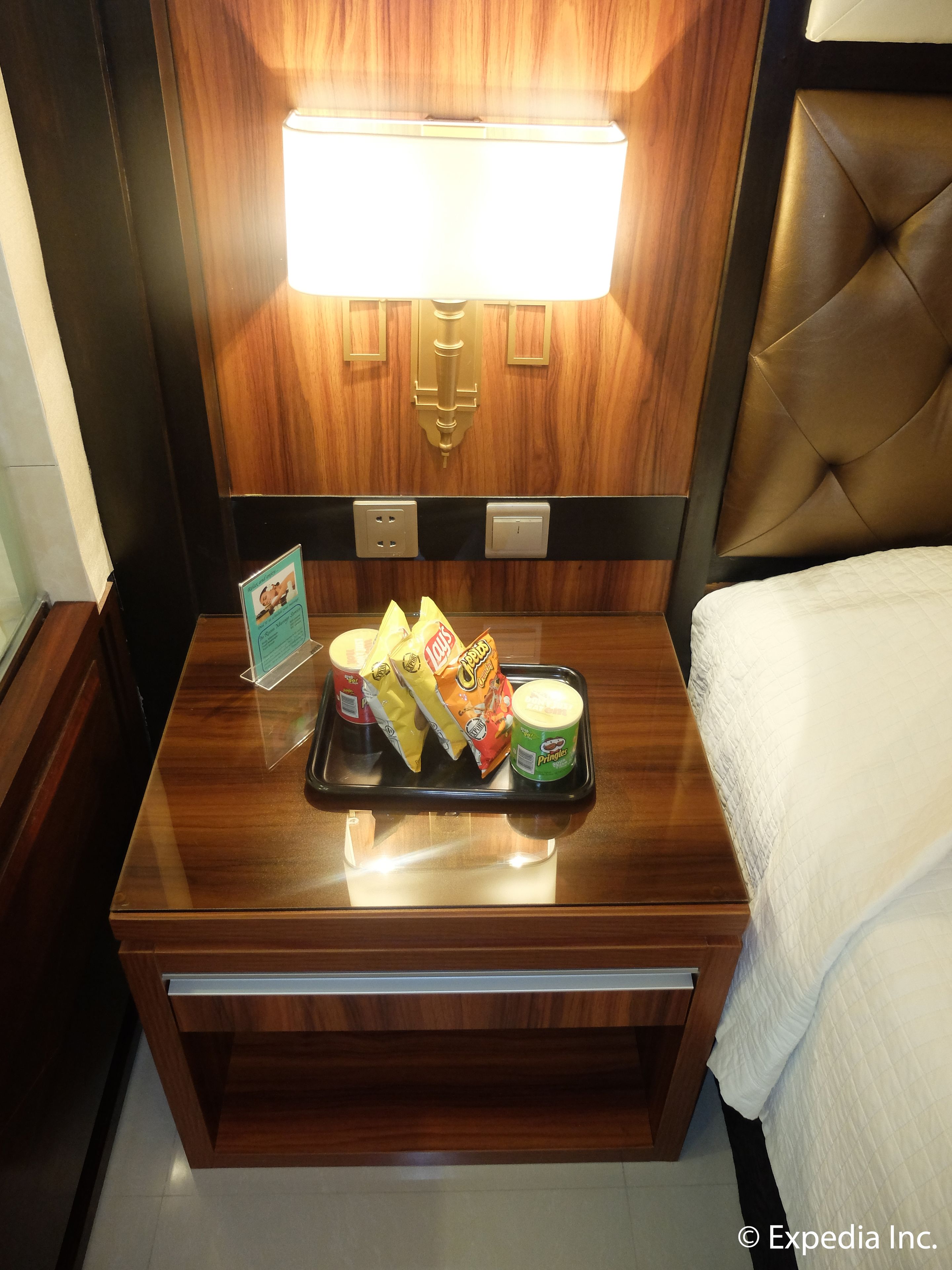 A wooden nightstand with a tray holding snacks and a container of Pringles.