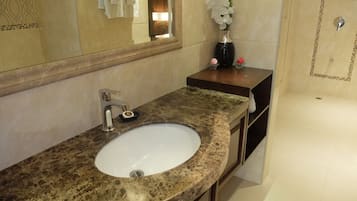 A bathroom with a marble sink, a mirror, and a vase with white flowers.