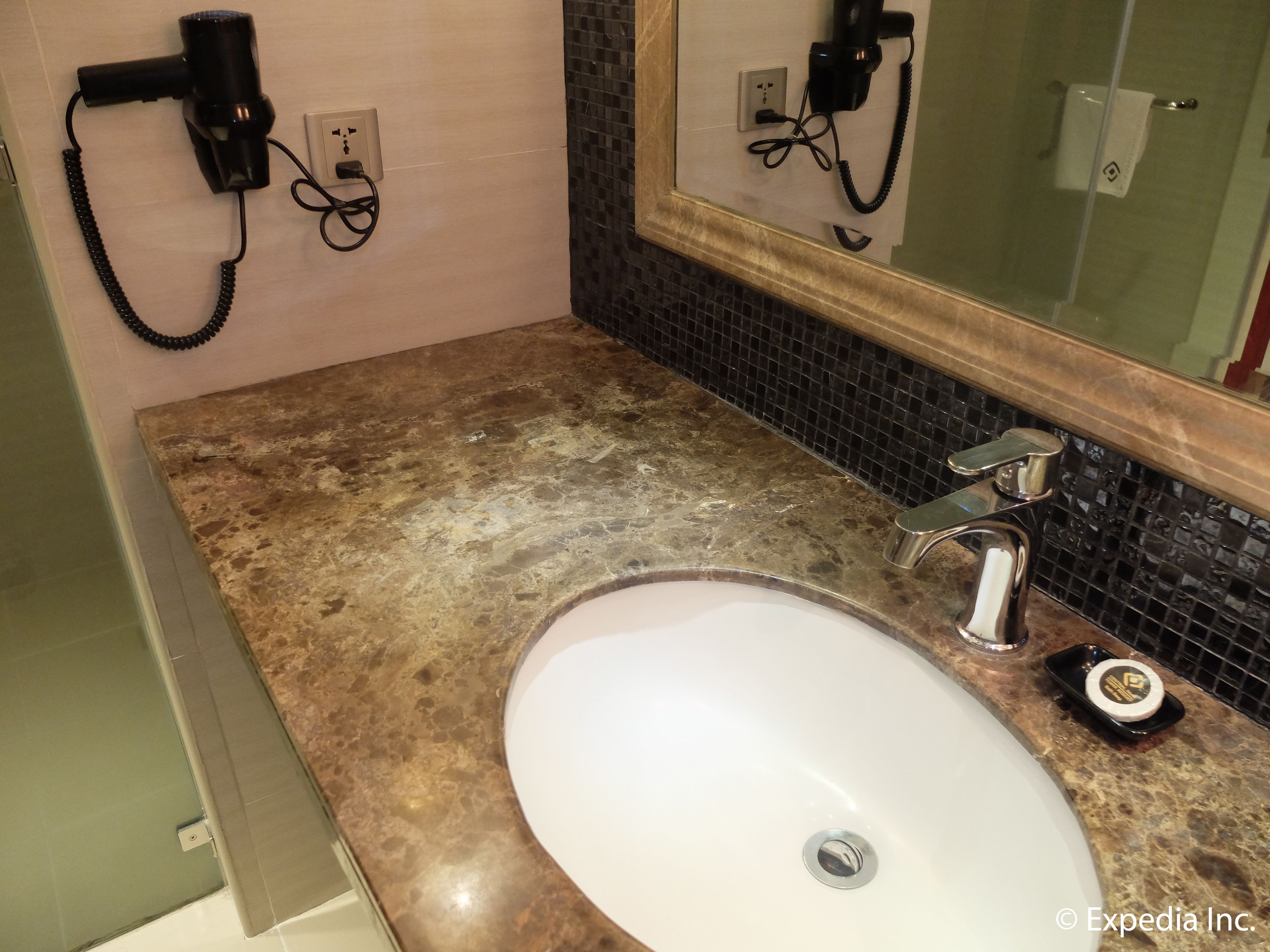 A bathroom with a white sink, a mirror, a hairdryer, and a towel rack.