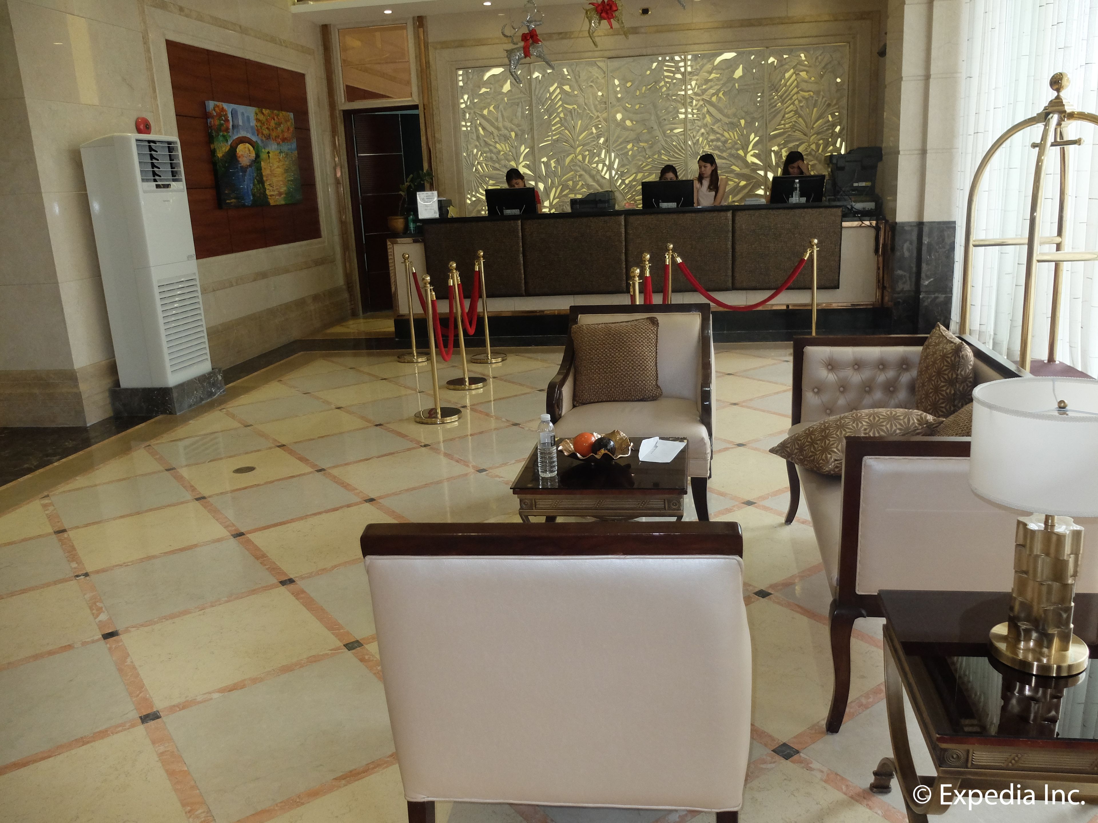 Un vestíbulo con mostrador de recepción, varios sillones, una mesa de centro y una lámpara decorativa.