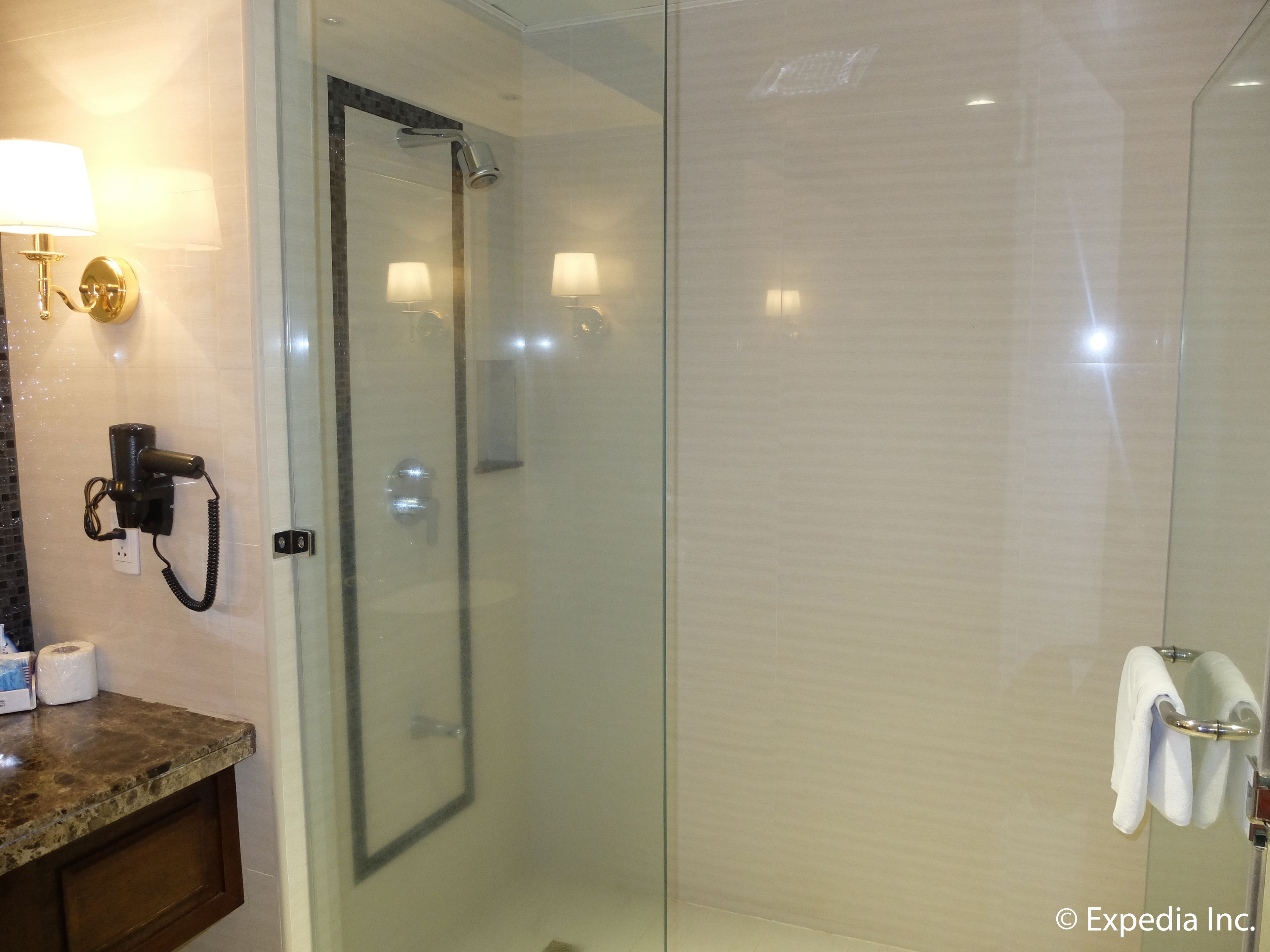 Un baño moderno con cabina de ducha de vidrio, tocador de mármol y un perchero para toallas.