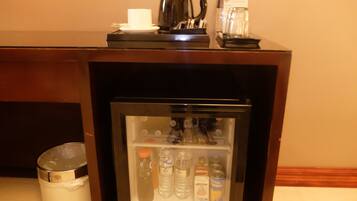 Un mini bar con una cafetera, una taza y agua embotellada.