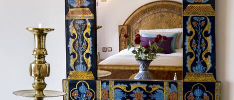 A room with a bed, a decorative mirror, and a brass lamp.