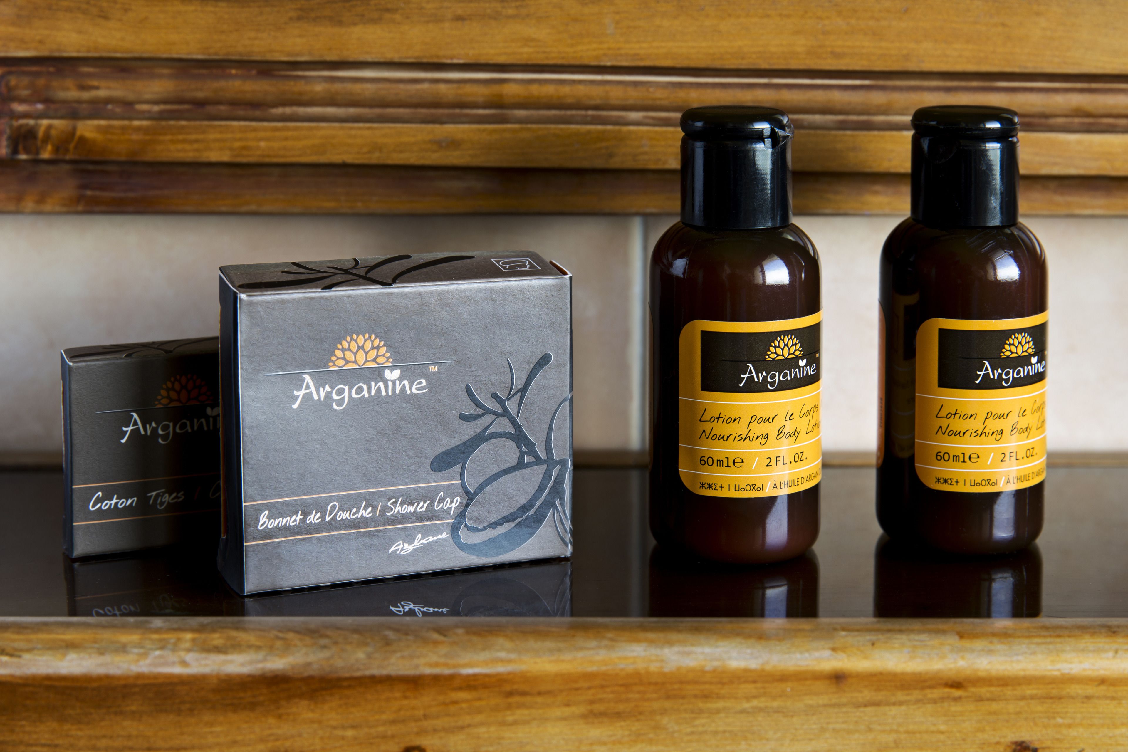 A box and two bottles of Arganine shower gel on a wooden surface.