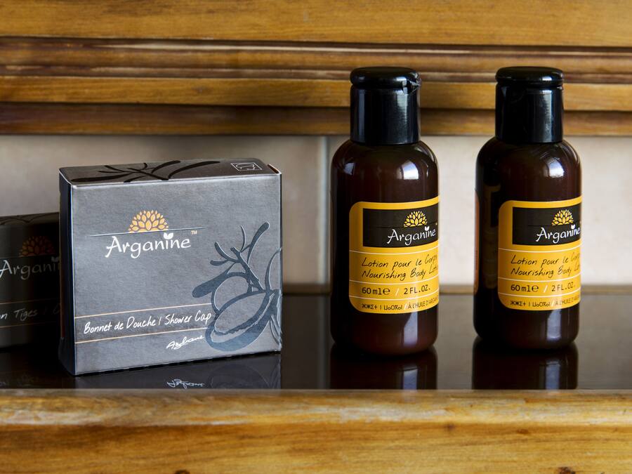 A box and two bottles of Arganine shower gel on a wooden surface.