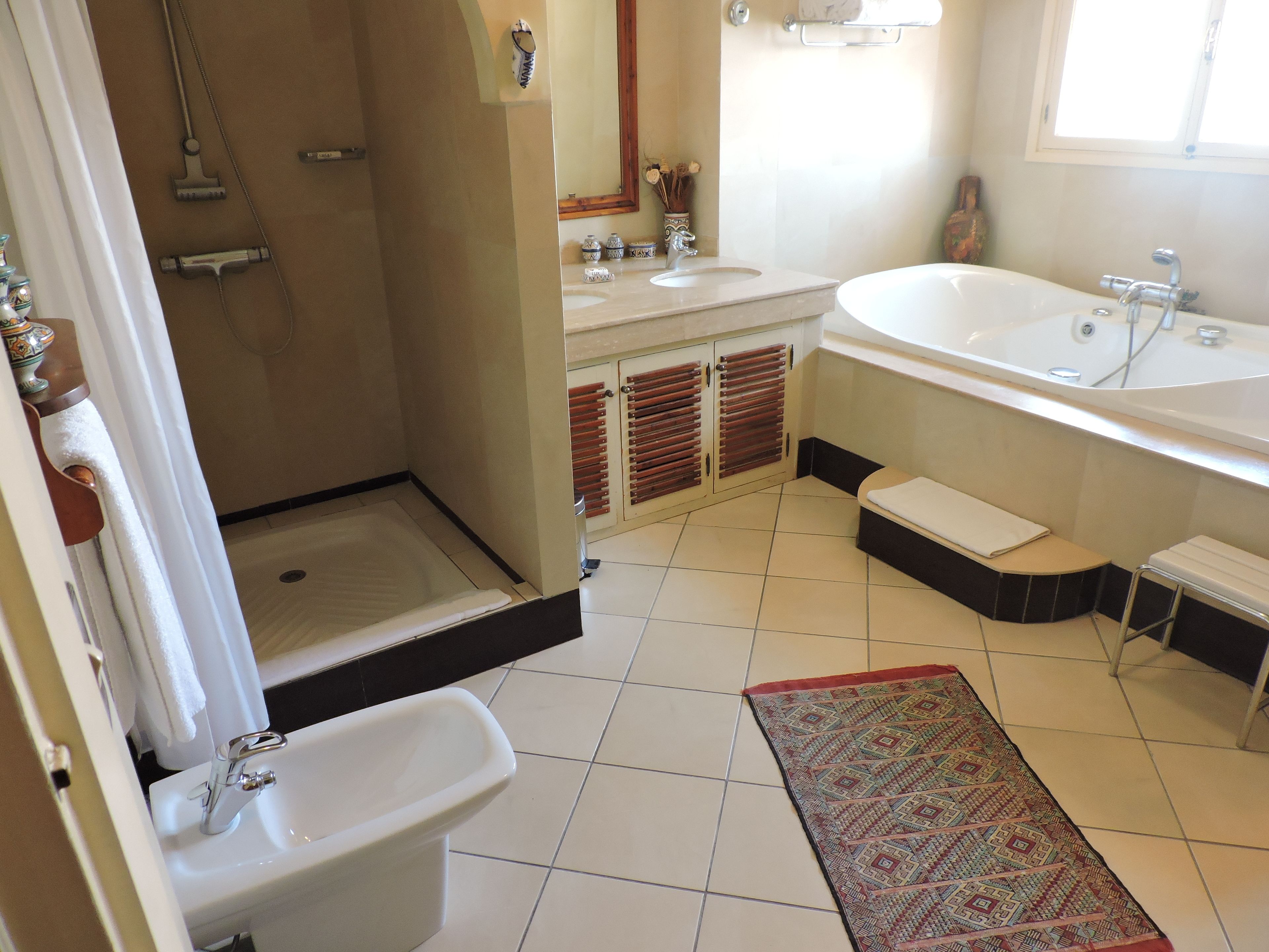 A bathroom with a shower, a sink, a toilet, a bathtub, and a window.
