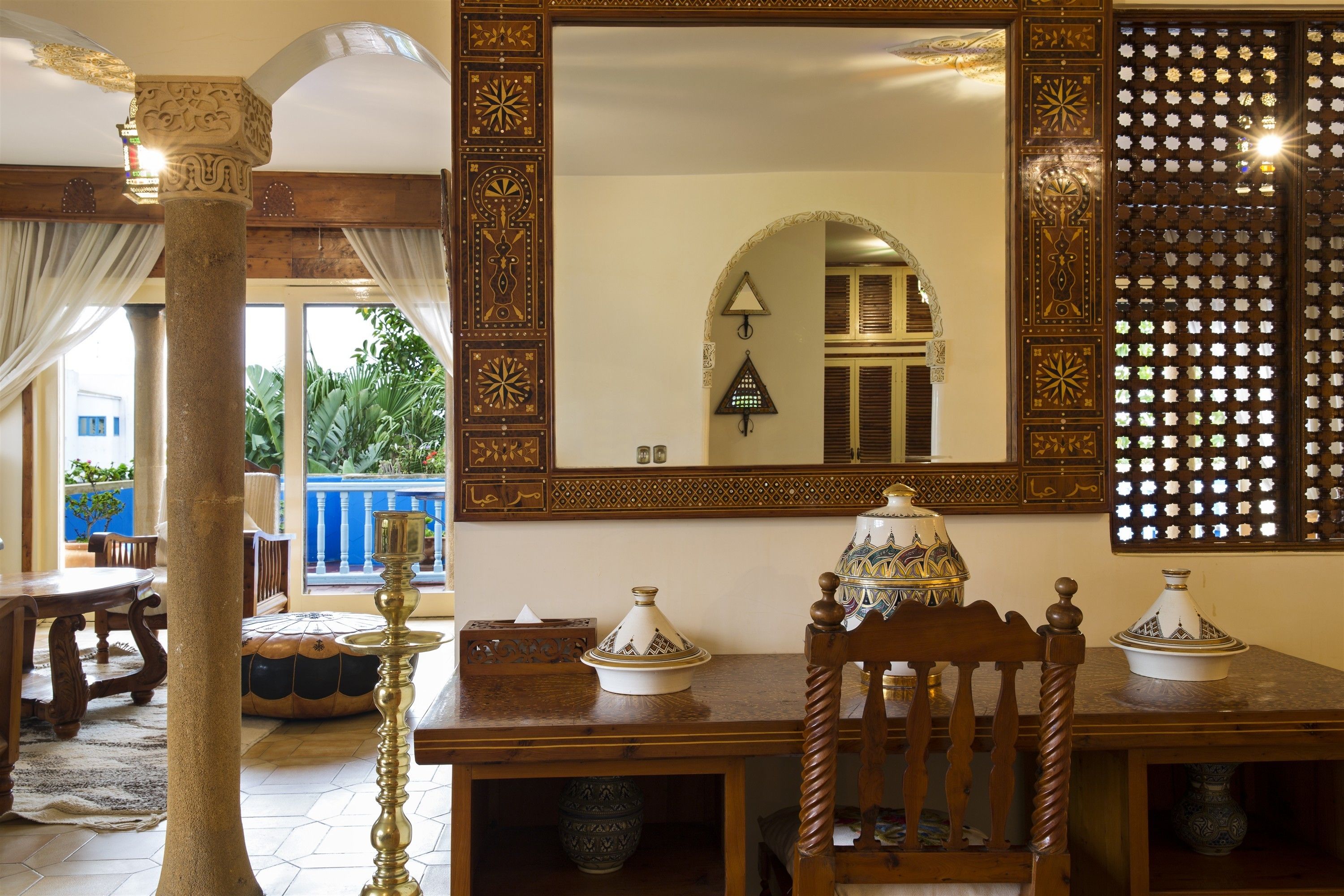 Ein traditionelles Interieur mit einem Holzesstisch, einem verzierten Spiegel und einer Wand mit Muster.