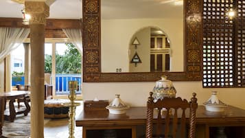 Ein traditionelles Interieur mit einem Holzesstisch, einem verzierten Spiegel und einer Wand mit Muster.