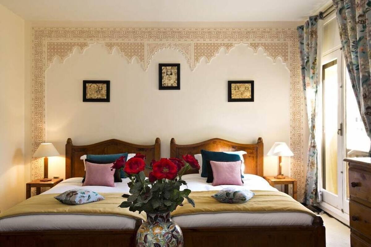 A double bed with a floral vase, two nightstands, and a decorative wall.
