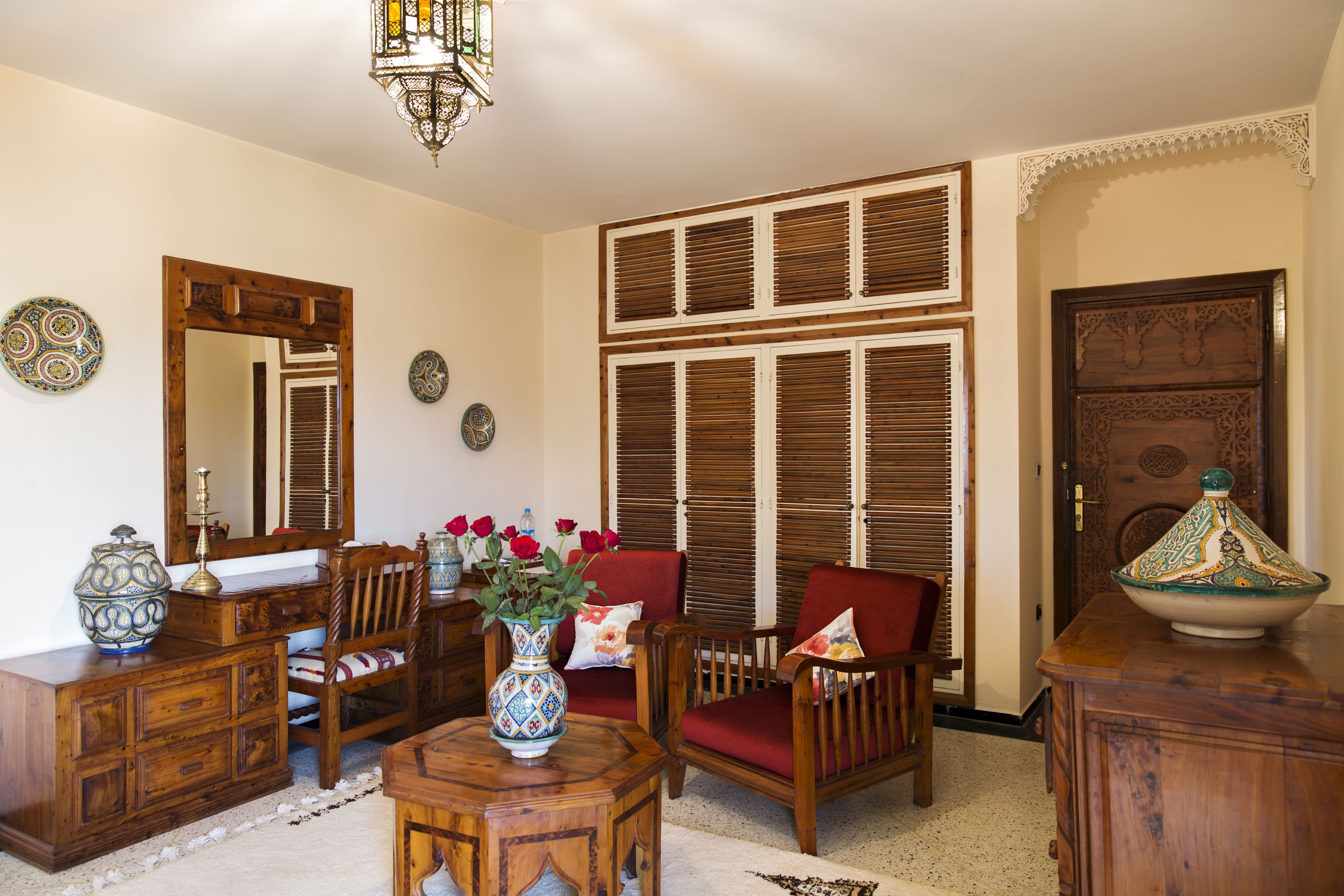 Un salon traditionnel avec des meubles en bois, un grand miroir et des assiettes décoratives.