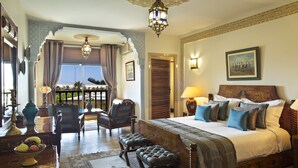 Quarto espaçoso com cama grande, vista para a varanda, teto trabalhado e decoração tradicional.