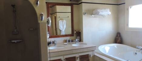 Une salle de bain avec une grande baignoire, deux lavabos, un miroir et un porte-serviettes.