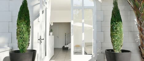 An open doorway leading to a bright interior space with a staircase and a potted plant.