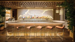 Una zona de bar con un letrero de Louis Vuitton, taburetes y una variedad de botellas.