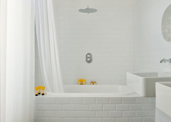 A modern bathroom with a white bathtub, a showerhead, and a sink with a mirror.