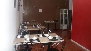 A dining area with tables set for tea service, a red wall, and a cabinet in the background. - Hôtel Victory (Marseille)