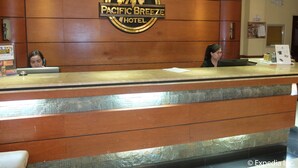 Bancada de recepção do Hotel Pacific Breeze, com design em painel de madeira e logotipo de palmeira.
