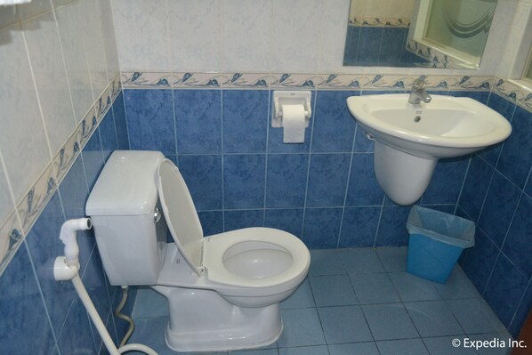 Un baño con inodoro, lavamanos y azulejos azules.