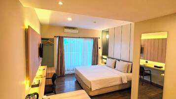 A hotel room with a bed, a desk with a chair, a small table with a tray, and a mirror.