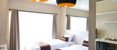 A hotel room with two beds, a desk, and a chair.