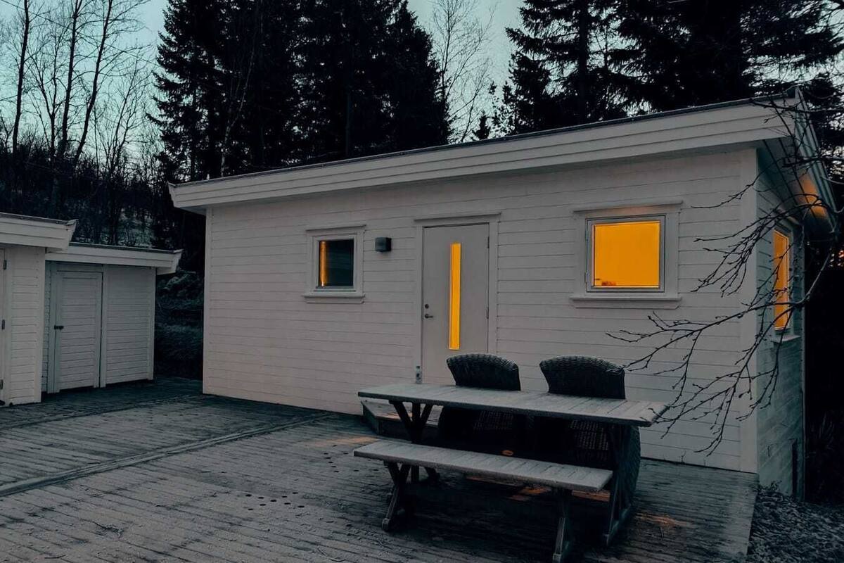 Un edificio pequeño de un piso con puerta principal, ventana y mesa de picnic.