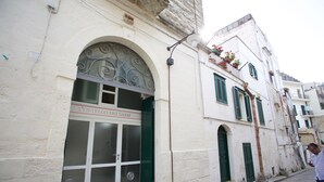 Um edifício com uma fachada identificada como "POSTELLO DEI SASSI".