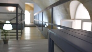 Um corredor com um banco, plantas em vasos e uma escada.