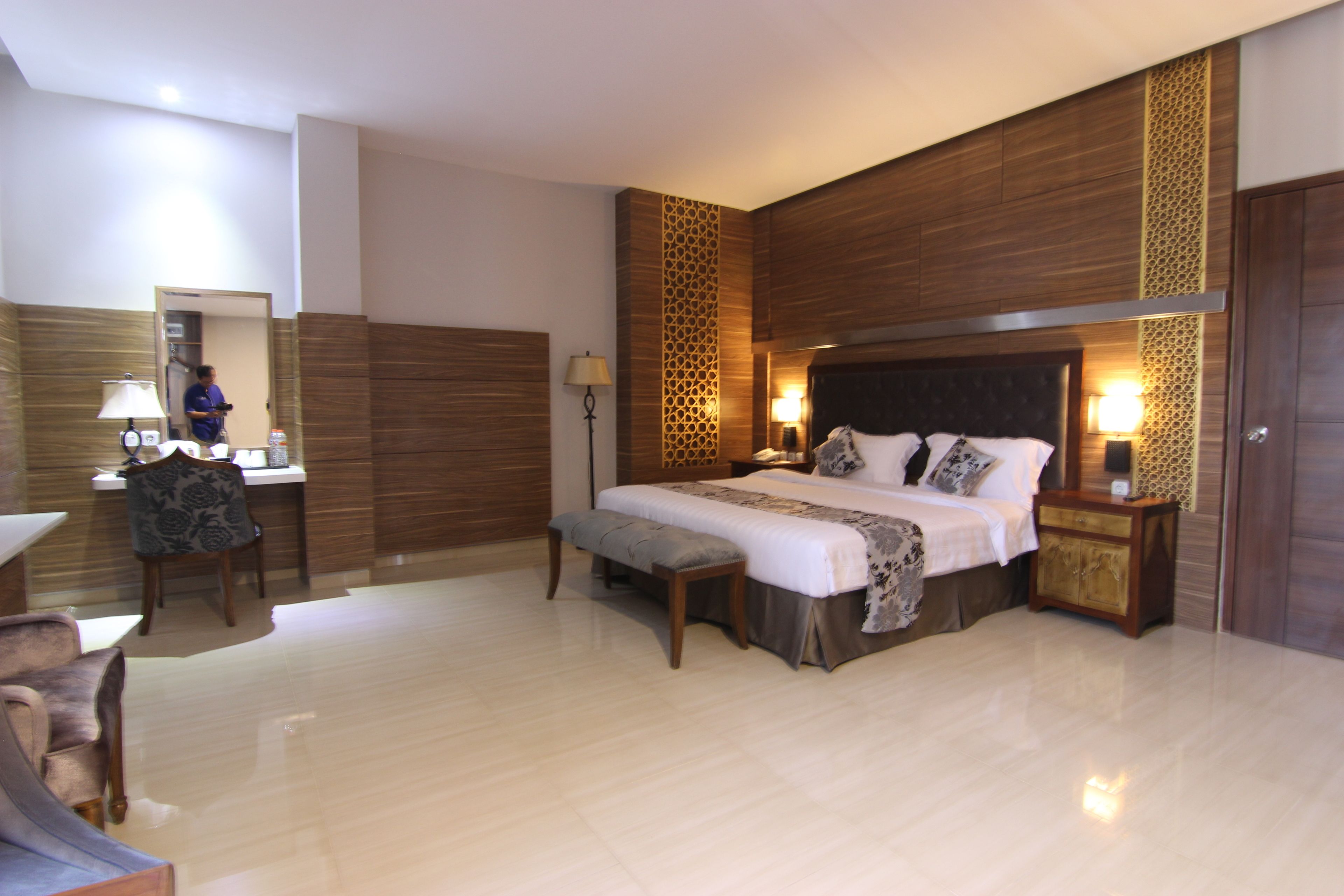 A spacious bedroom with a large bed, bedside tables, a desk, and a chair.