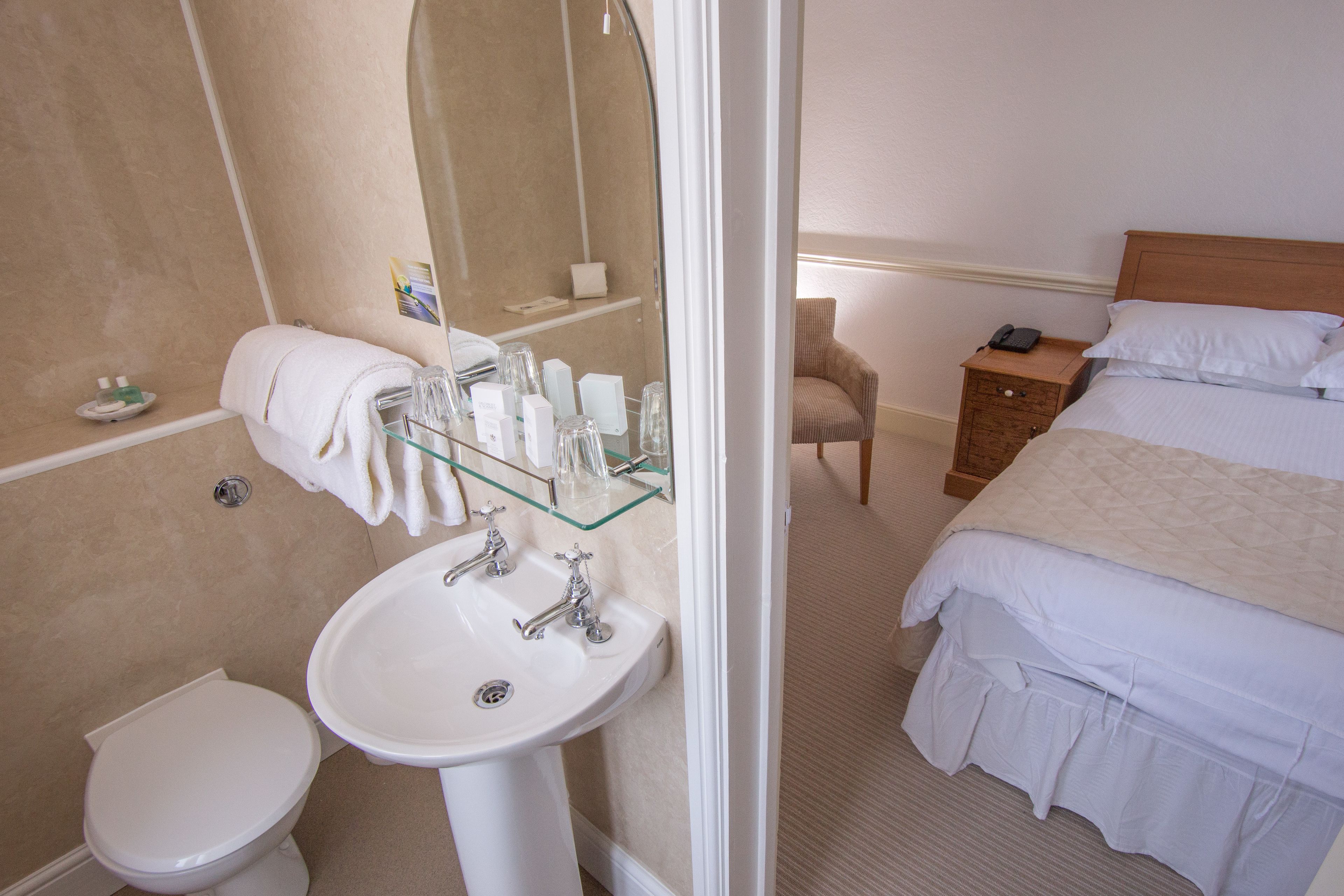 A hotel bathroom with a white sink, toilet, and glass shower enclosure.