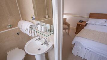 A hotel bathroom with a white sink, toilet, and glass shower enclosure.